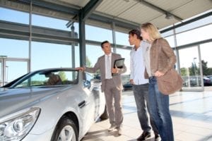 Car seller with couple in car dealership