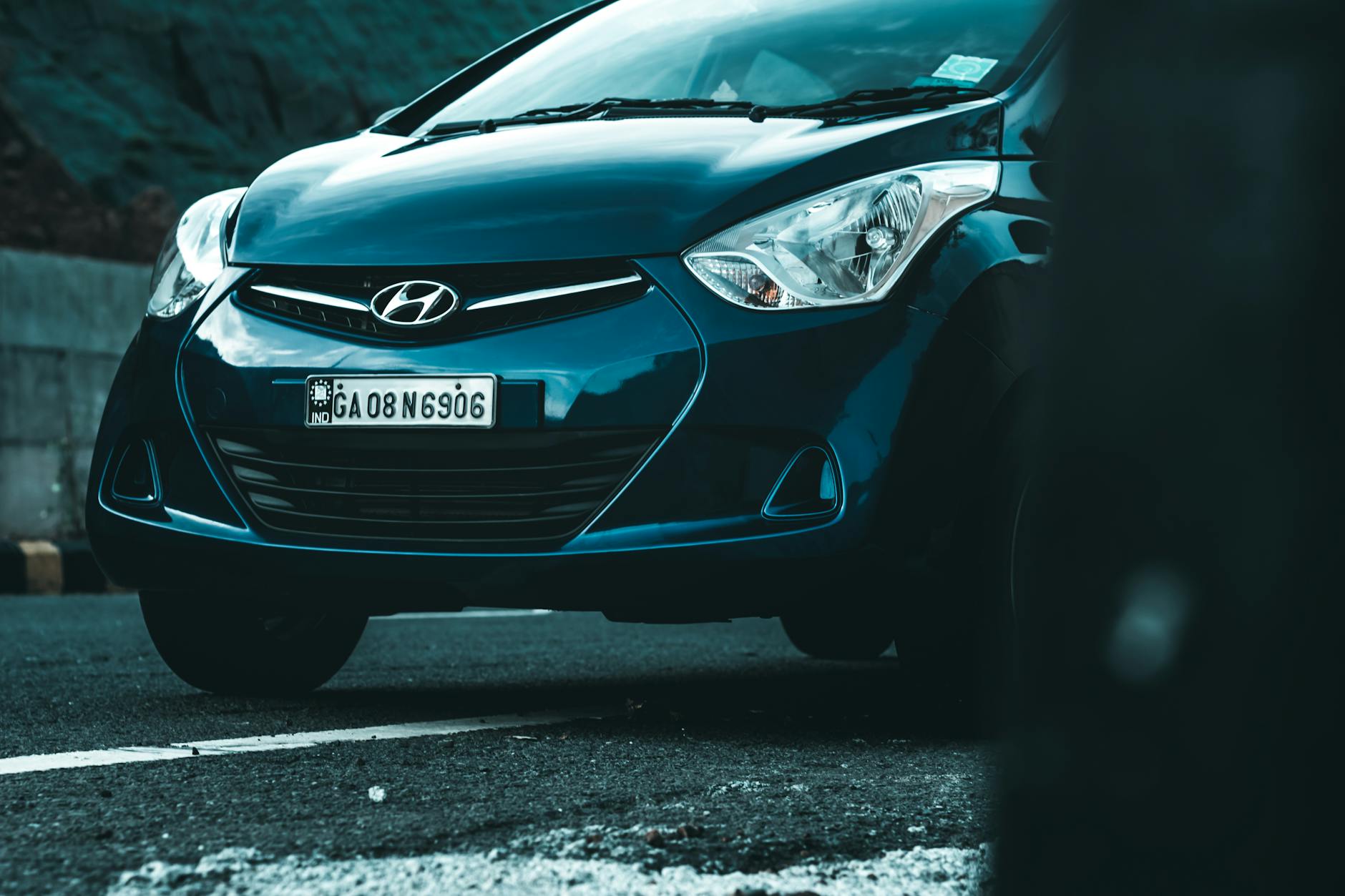 Véhicule Hyundai de couleur bleu foncé stationné sur une route, avec un accent sur la calandre et les phares avant.