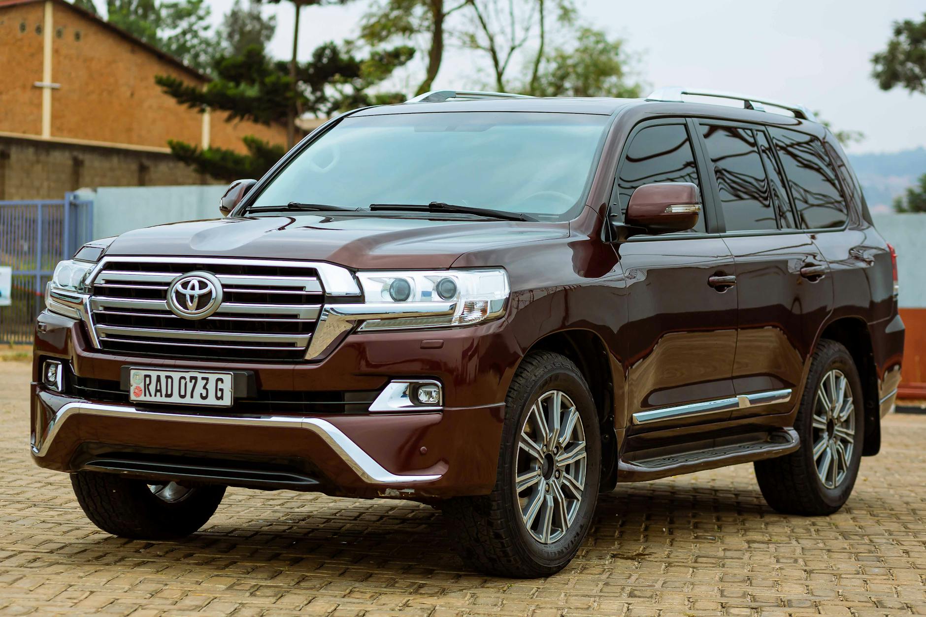 Véhicule utilitaire sport Toyota de couleur brun, stationné sur un pavé, avec des bâtiments flous en arrière-plan.