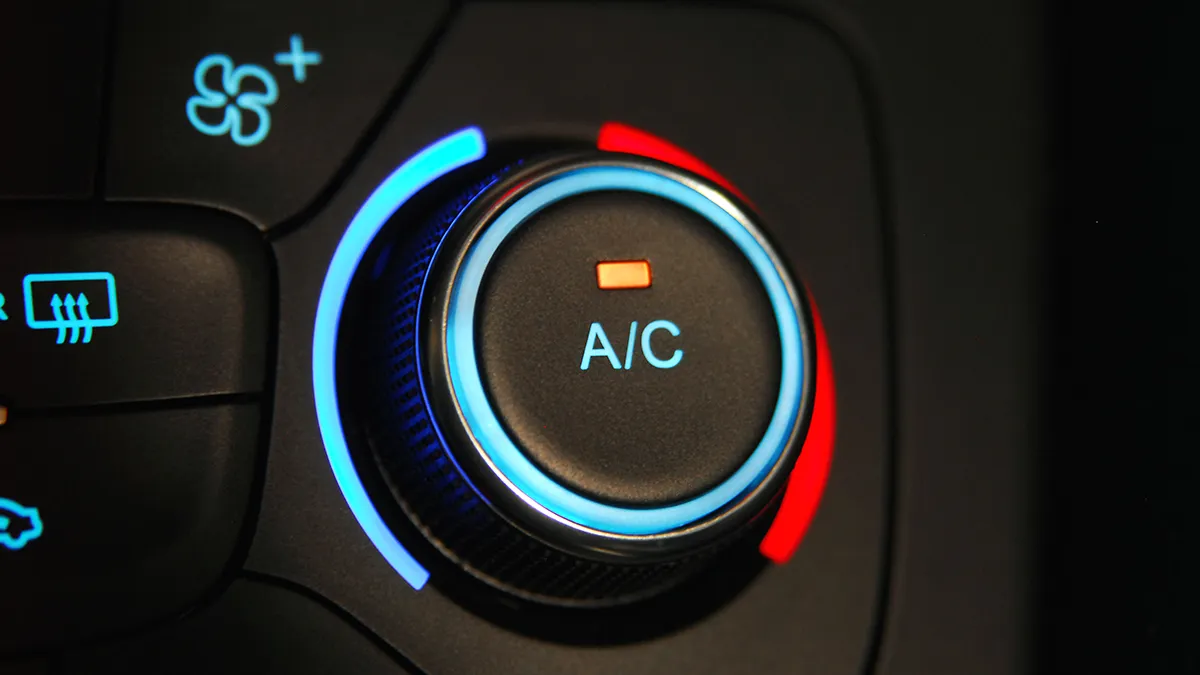 Bouton de climatisation avec indicateur lumineux, entouré de lumières bleue et rouge, sur un tableau de bord automobile.