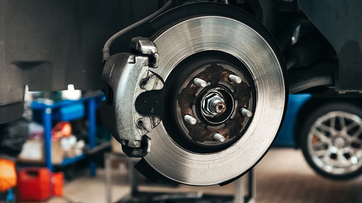 Disque de frein avec étrier, montrant des composants mécaniques, dans un environnement d'atelier automobile.