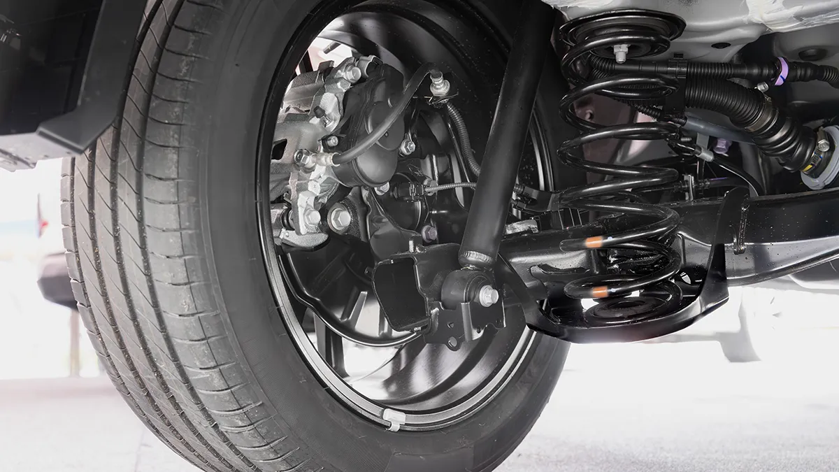 Détail d'un système de suspension de véhicule, montrant un ressort, un amortisseur et un pneu sur une jante.