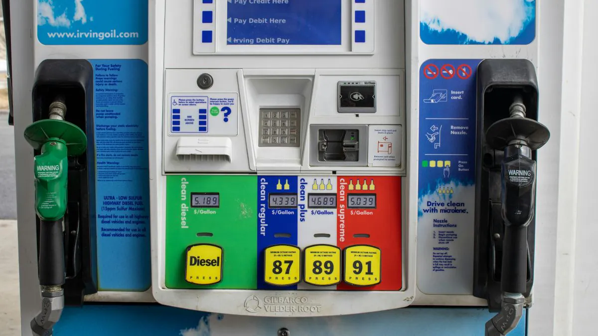 Pompe à essence avec plusieurs pistolets de carburant, affichant les prix pour l'essence ordinaire, l'essence super et le diesel.